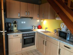a kitchen with a sink and a stove top oven at Les Loges du Lac - Appartement avec Terrasse in Gérardmer