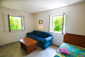 ein Wohnzimmer mit einem blauen Sofa und 2 Fenstern in der Unterkunft Guest House Saga in Herceg-Novi