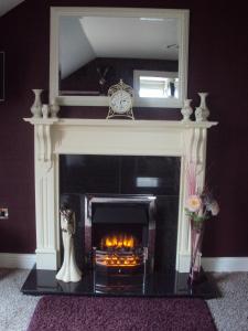 a fireplace with a mirror above it with a fire place at Causeway Lodge in Bushmills