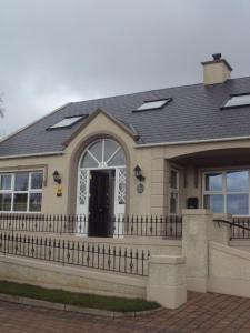 una casa con techo negro y valla en Causeway Lodge, en Bushmills