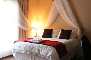 Micasa Sucasa Guesthouse في Lephalale: غرفة نوم بسرير ابيض كبير مع بطانيه حمراء