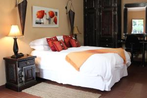 Micasa Sucasa Guesthouse في Lephalale: غرفة نوم بسرير ذو شراشف بيضاء ومخدات حمراء