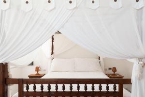 Quartara Boutique Hotel في بانايا: غرفة نوم مع سرير مظلة مع ستائر بيضاء