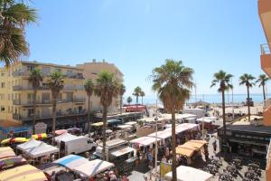 una concurrida calle de la ciudad con palmeras y sombrillas en HACIENDA- Grand studio dans le centre avec vue mer en Canet-en-Roussillon