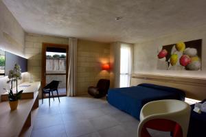 a bedroom with a blue bed and a desk and a table at Cave Bianche Hotel in Favignana