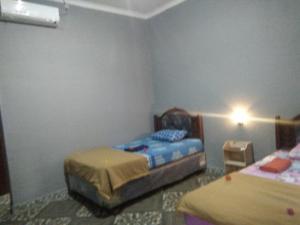 a bedroom with two beds and a light on the wall at Sawe Homestay in Kuta Lombok