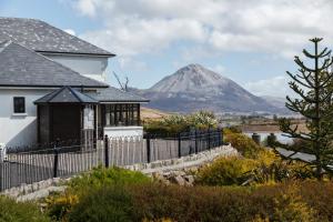 a house with a fence and a mountain in the background at An Ch&uacute;irt Hotel, Gweedore, Donegal in Gweedore