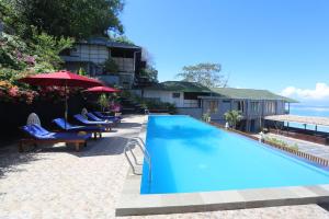 a large blue swimming pool with chairs and umbrellas at Bastianos Bunaken Dive Resort in Bunaken