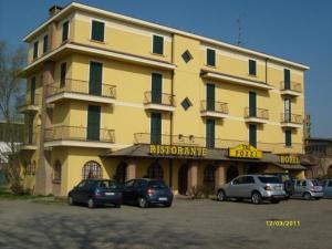 żółty budynek z samochodami zaparkowanymi przed nim w obiekcie Albergo Tre Pozzi w mieście Fontanellato