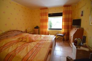 Schlafzimmer mit einem Bett, einem TV und einem Fenster in der Unterkunft Landhotel Maarheide in Niederdürenbach