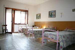 um quarto com quatro camas e uma mesa e cadeiras em Albergo Anna em Ciampino