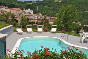 a swimming pool with chairs and a view of a city at Hotel Villa Stella in Cascia