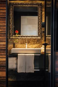 a bathroom with a sink and a mirror and towels at Hotel Bagués, a Small Luxury Hotel of the World in Barcelona