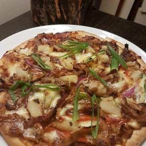 a pizza on a white plate on a table at Junction Hotel Moora in Moora