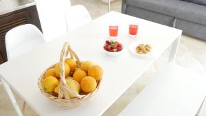 a basket of fruit on a white table with drinks at Casas da Praia in Manta Rota