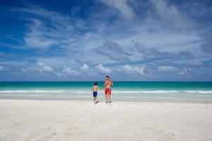 Un hombre y un niño parados en una playa en Catalonia Playa Maroma - All Inclusive, en Playa del Carmen