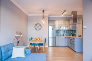 kuchnia i salon z niebieską kanapą i stołem w obiekcie Apartament Villa Nautica w Rydzewie