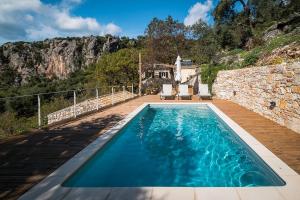 a swimming pool in front of a stone house at Castelli Olive Press in Acharavi