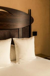 a bed with white pillows and a wooden headboard at Hotel Bagués, a Small Luxury Hotel of the World in Barcelona