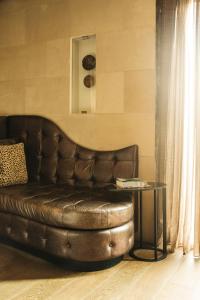 a brown leather couch in a living room with a table at Hotel Bagués, a Small Luxury Hotel of the World in Barcelona