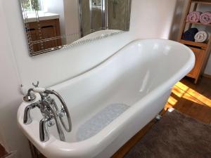 a white bath tub in a bathroom with a mirror at Central Boscastle studio flat in Boscastle