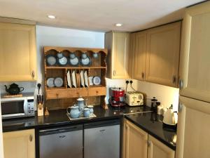 uma cozinha com armários de madeira e bancadas pretas em Central Boscastle studio flat em Boscastle