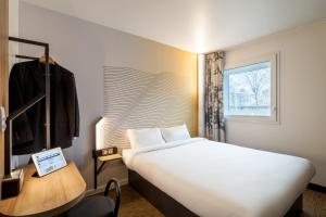 熱訥維耶的住宿－B&B HOTEL Paris Gennevilliers Asnières，一间设有大床和窗户的酒店客房