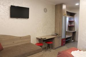 a bedroom with a bed and a desk with a television on the wall at Dikii Med in Geletintsy