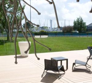 2 chaises et une table sur une terrasse avec un parc dans l'établissement Hotel le Crouesty, à Arzon