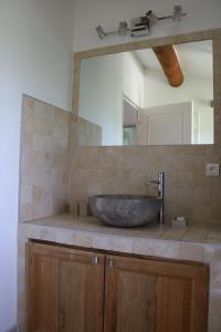 y baño con lavabo de piedra y espejo. en Charmante maison de village en Cucuron