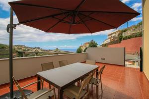 a table and chairs on a balcony with an umbrella at Villas Quinta da Lapa by AnaLodges in Câmara de Lobos