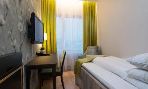 a bedroom with a bed and a desk with a television at Thon Hotel Opera in Oslo