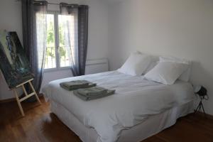 Un dormitorio con una cama blanca con toallas. en Charmante maison de village en Cucuron