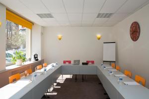 una sala de conferencias con mesas largas y sillas naranjas en Hôtel des Reignaux, en Lille