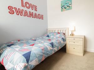 1 dormitorio con 1 cama y una señal que lee la variación del amor en Swanage Bay Apartment, en Swanage
