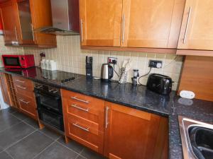 a kitchen with wooden cabinets and a black counter top at West Shore Cottage in Llandudno
