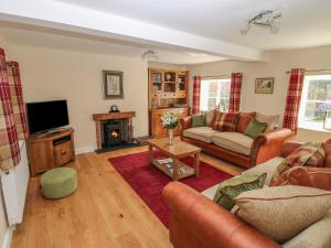 a living room with a couch and a tv at Firtree Cottage in Ashby de la Zouch
