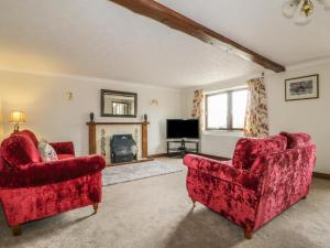 a living room with two red chairs and a fireplace at Woodhead Farm Cottage in Penrith
