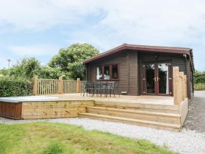 a small cabin with a deck and a table at Oak Lodge in Falmouth +3 photos