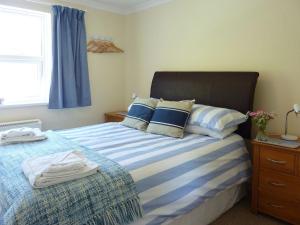 a bedroom with a bed with blue and white sheets and a window at Stones Throw in Saint Mawes