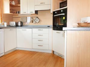 a kitchen with white cabinets and black appliances at Oak Lodge in Falmouth