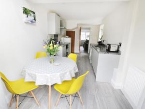 une cuisine et une salle à manger avec une table et des chaises jaunes dans l'établissement 25 Shakespeare Street, à Stratford-upon-Avon