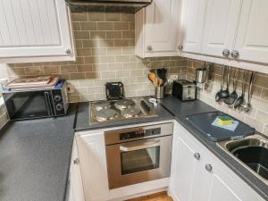 a kitchen with a stove top oven next to a microwave at Heugh Barn in Thwaite