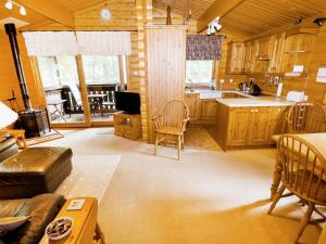 a large kitchen with wooden cabinets and a living room at Lodge 8 in Legbourne