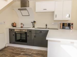 a kitchen with white cabinets and a sink at Squirrels Drey in Little Dunham