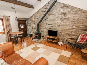 a living room with a stone wall and a fireplace at Heugh Barn in Thwaite