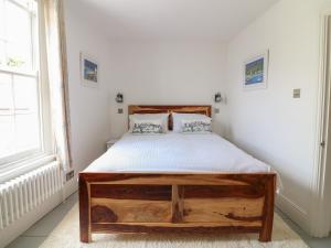 a bedroom with a wooden bed and a window at Sunny Cottage in Torpoint