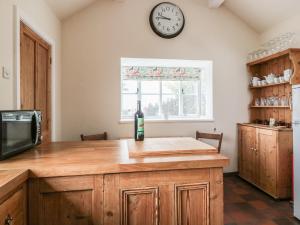 a kitchen with a counter with a clock on the wall at Lilac Cottage in Great Malvern +15 photos