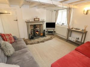 a living room with a couch and a fireplace at Box Tree Cottage in Buxton