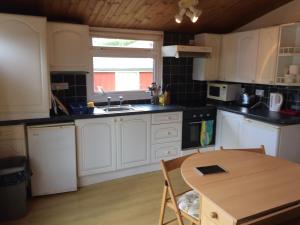 a kitchen with white cabinets and a wooden table at Pantyrathro International Hostel in Carmarthen